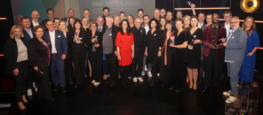 Gruppenfoto der Gewinner und Gewinnerinnen des Bremer Fernseh- und Digitalpreises 2024 auf der Bühne